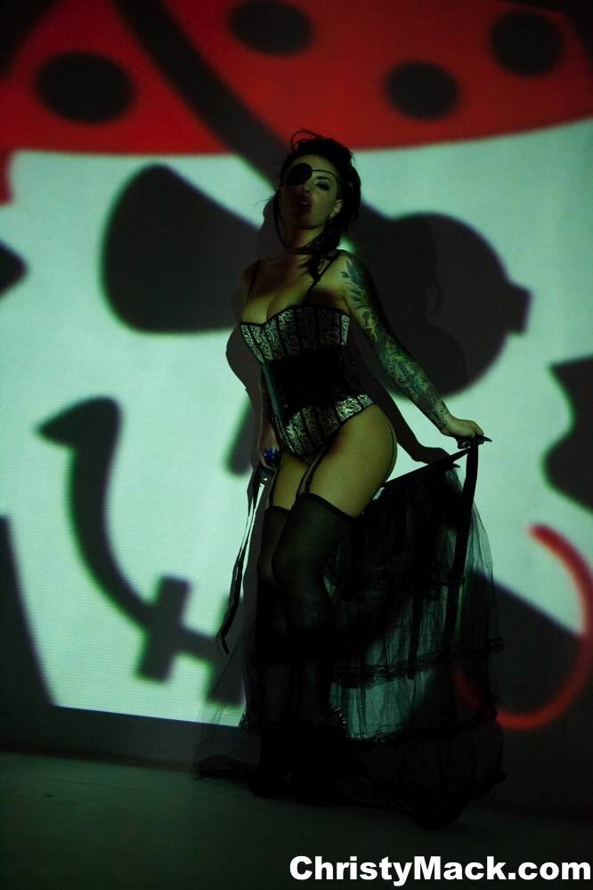 Solo girl Christy Mack wears an eye patch and lingerie while posing in shadows - #5