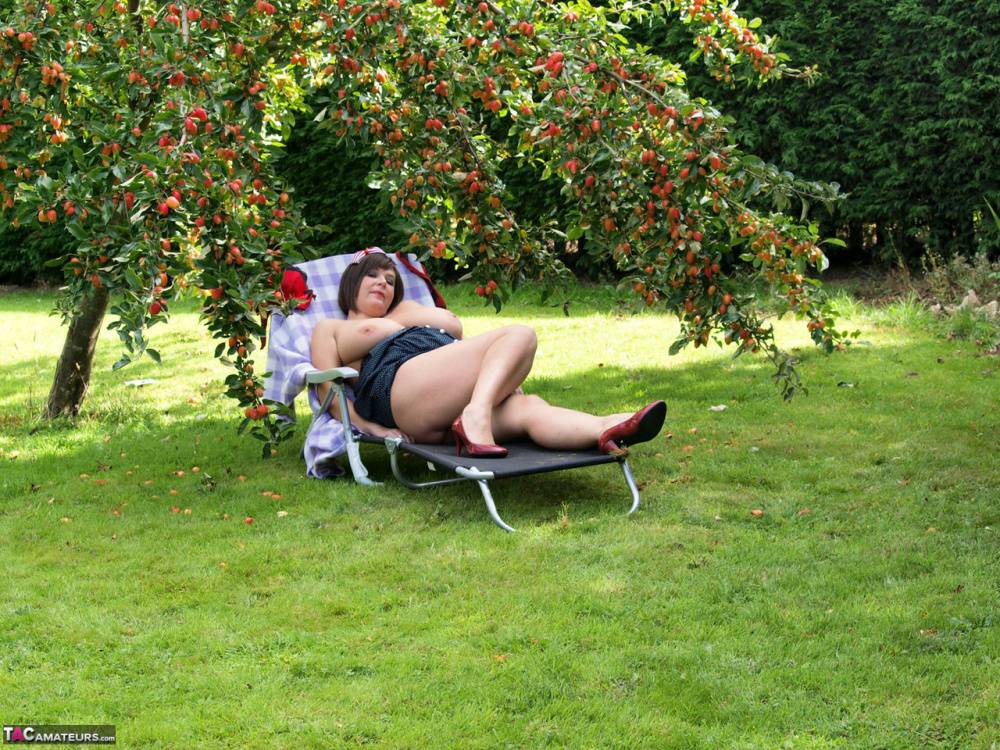 Plump amateur Roxy displays her huge boobs and bald cunt under a fruit tree - #4