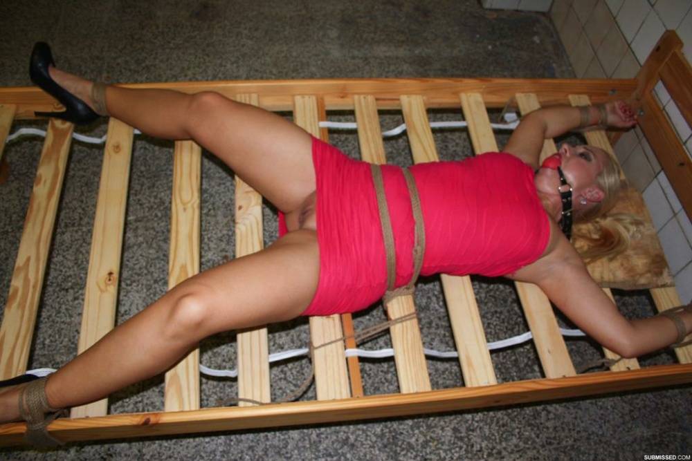 Ball gagged blond female struggles against rope restraints with dress hiked up - #16