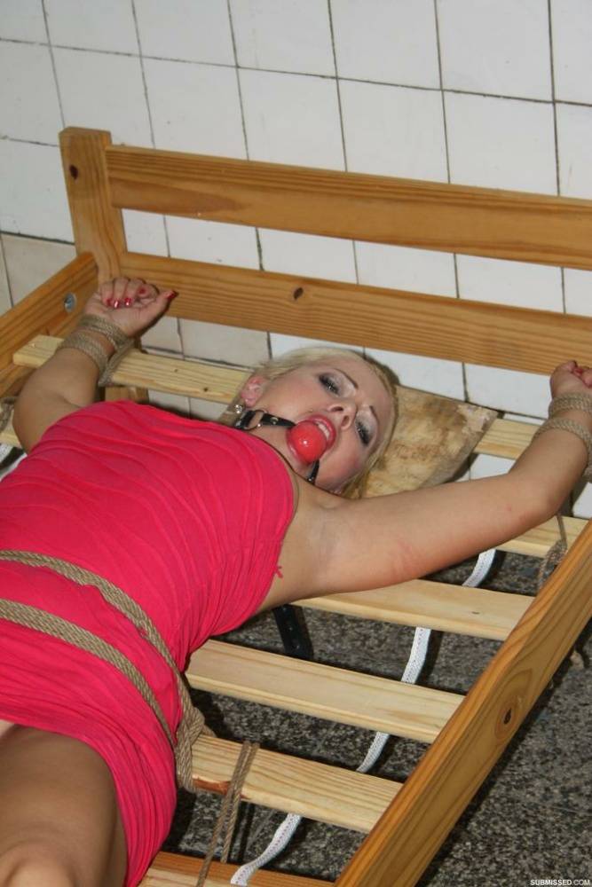 Ball gagged blond female struggles against rope restraints with dress hiked up - #4