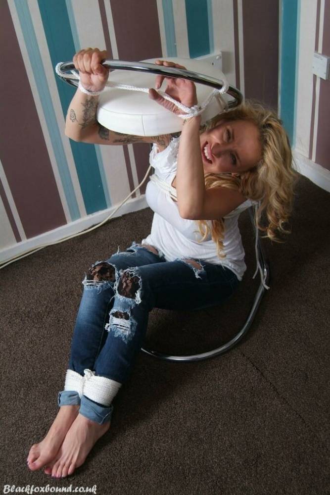 Fully clothed blonde Katie C struggles while restrained with rope bindings | Photo: 916062