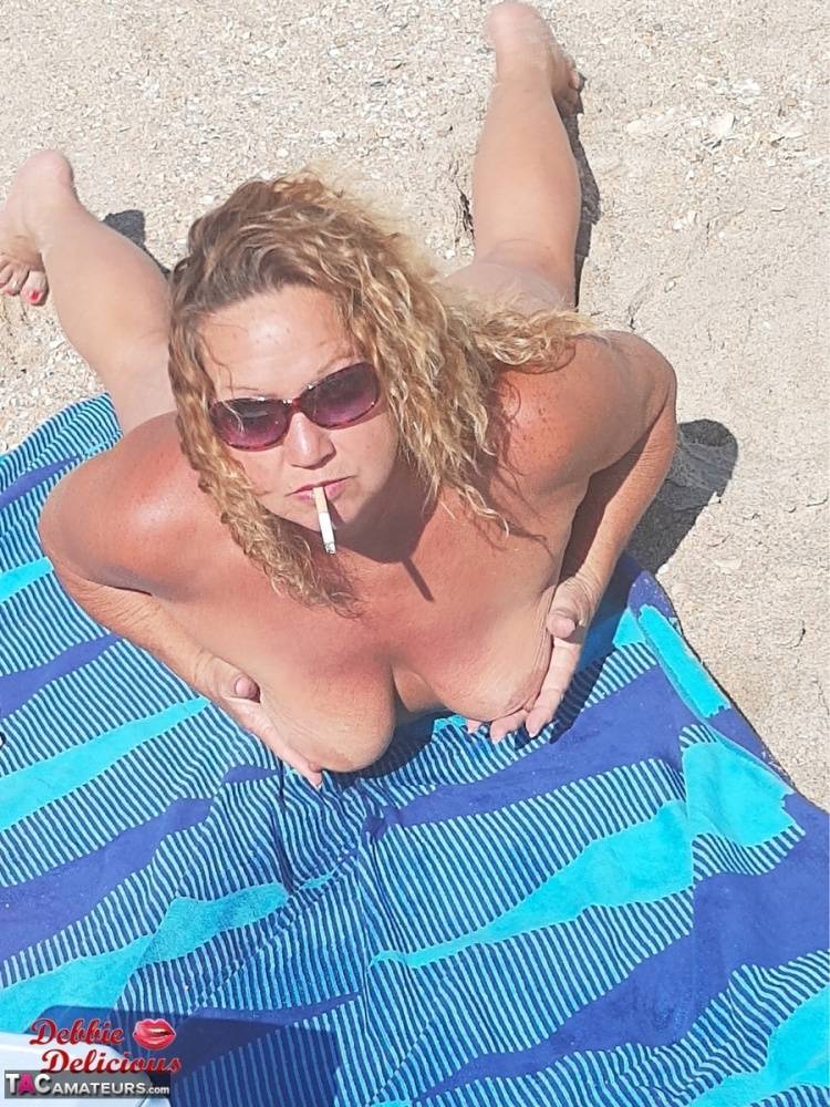 Older amateur Debbie Delicious smokes while sunbathing in the nude on a beach - #13