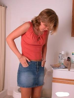 Amateur girl Karen hikes her denim skirt in the bathroom to expose her panties on realgirlsweb.com