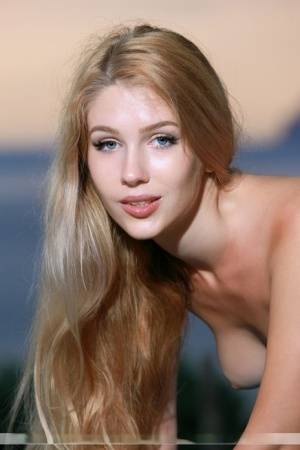 Beautiful blonde with long hair Xana D poses totally naked near the ocean on realgirlsweb.com