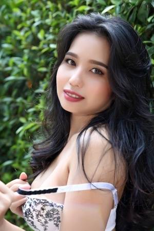 Beautiful Asian girl Norah gets totally naked next to a hedge in a garden on realgirlsweb.com